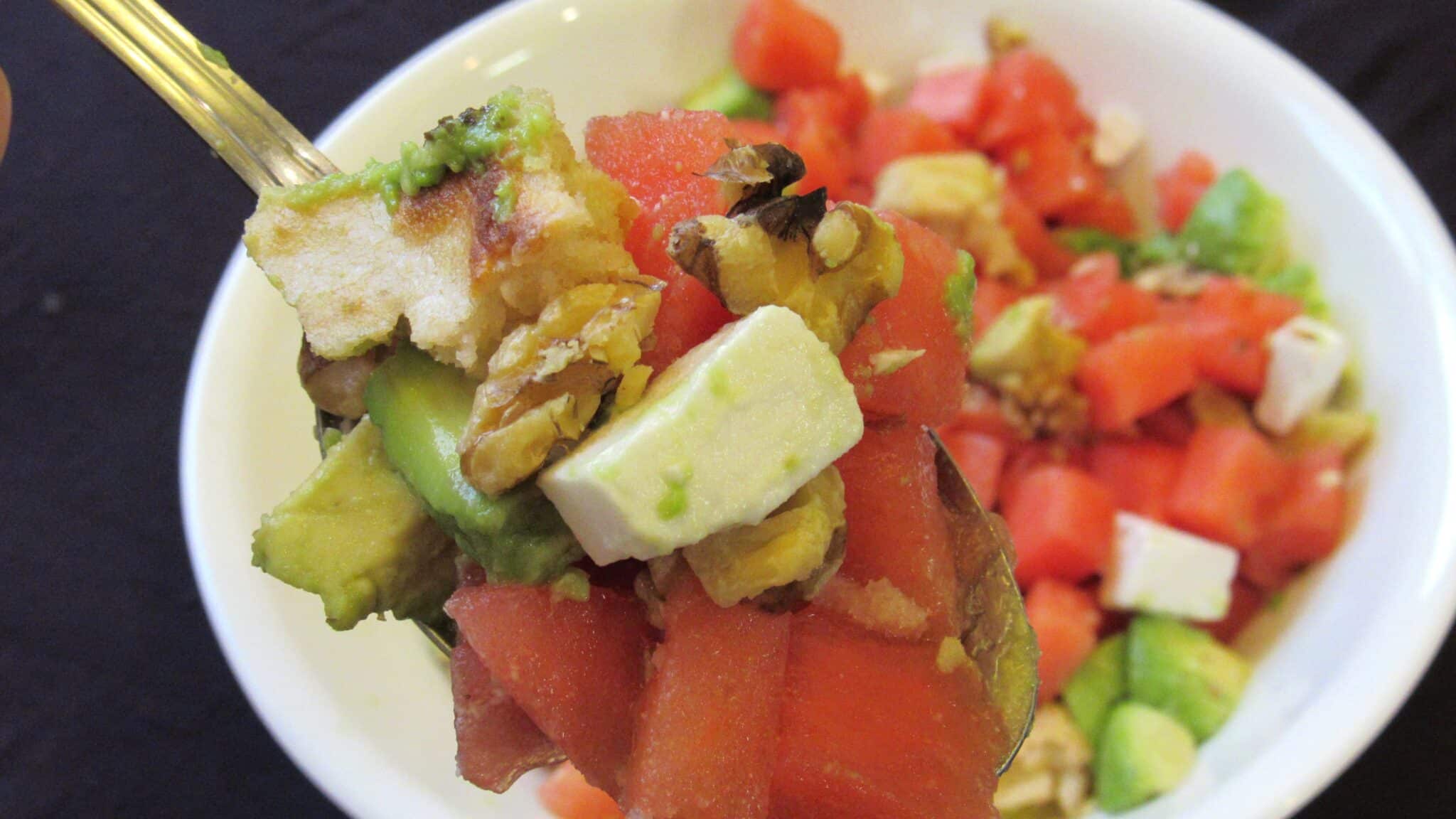 All the watermelon salad ingredients are mixed and served—a close-up image of a spoon full of watermelon salad.
