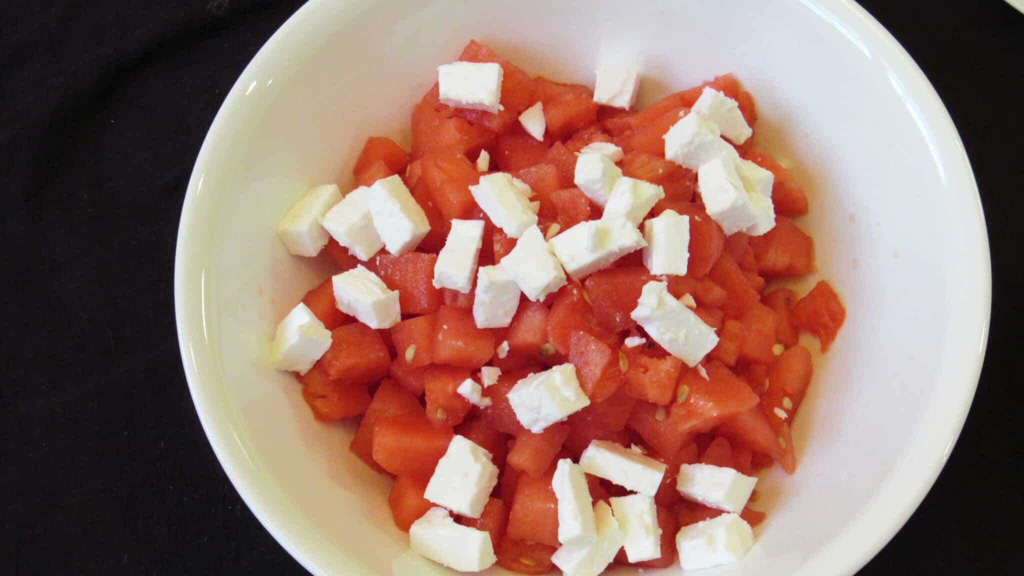 Diced watermelon and diced feta cheese in a white bowl.