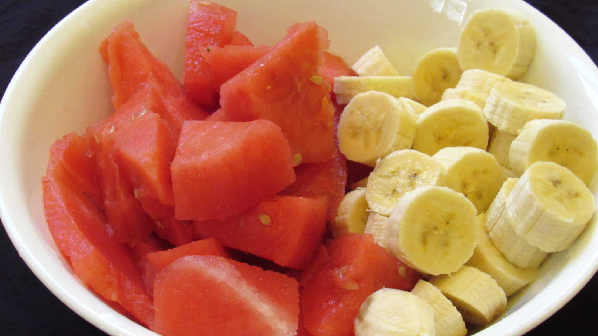 Diced watermelon and popsicles in a white bowl.