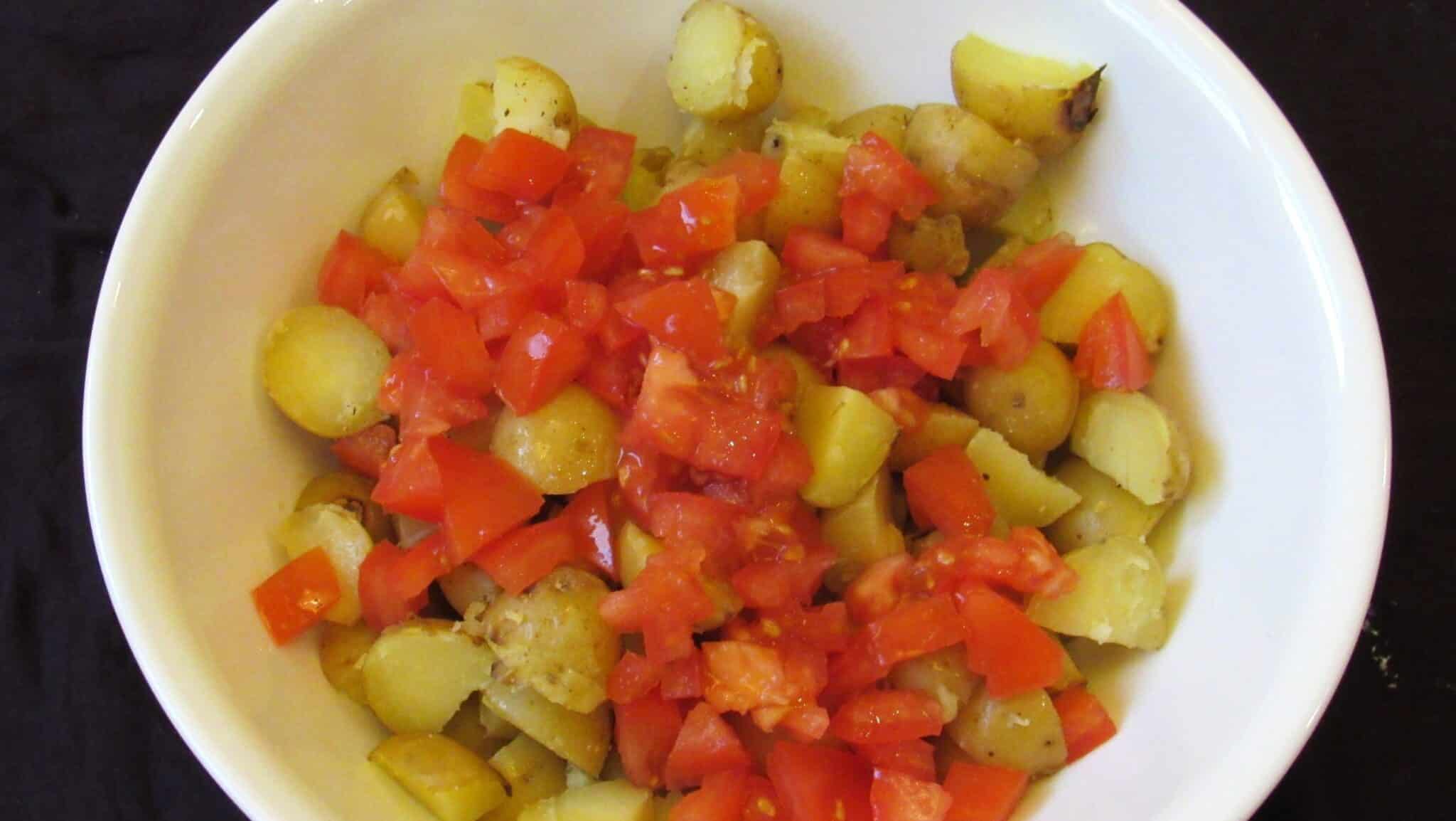 Diced cooked potatoes and diced tomatoes in a white bowl.