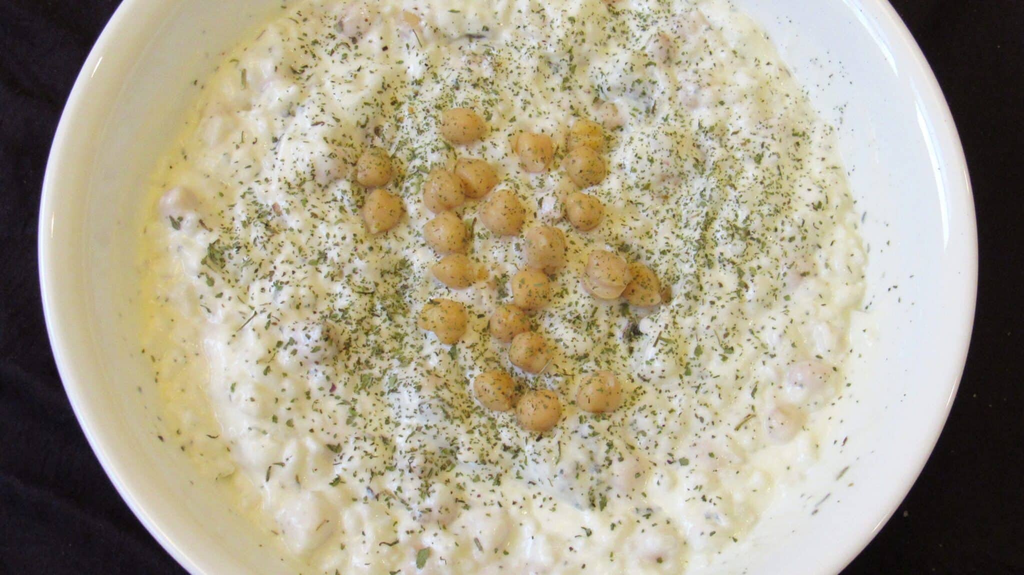 Chickpea salad with yogurt served in a white bowl.