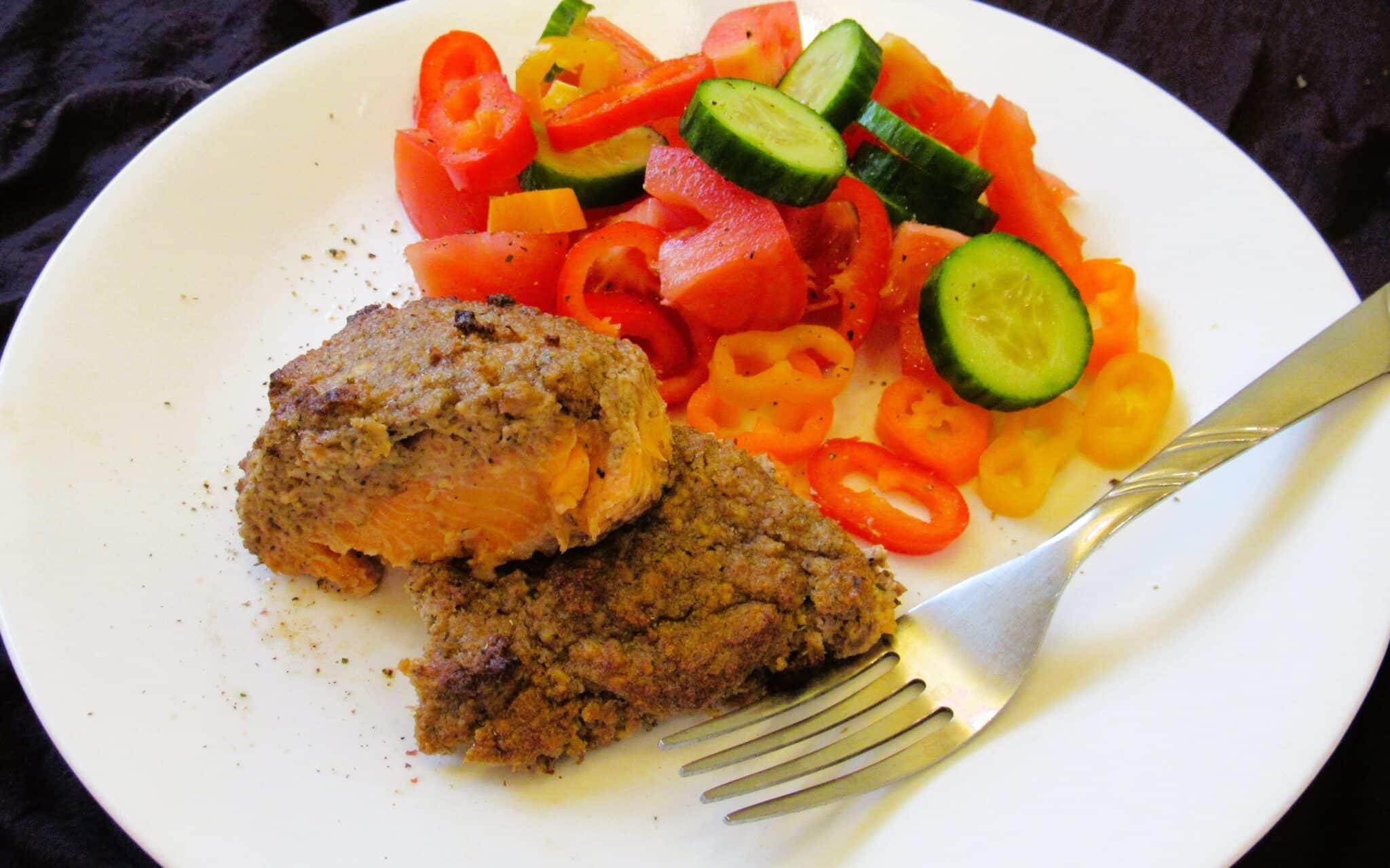 the walnut crust baked salmon on a plate with fresh salad and fork