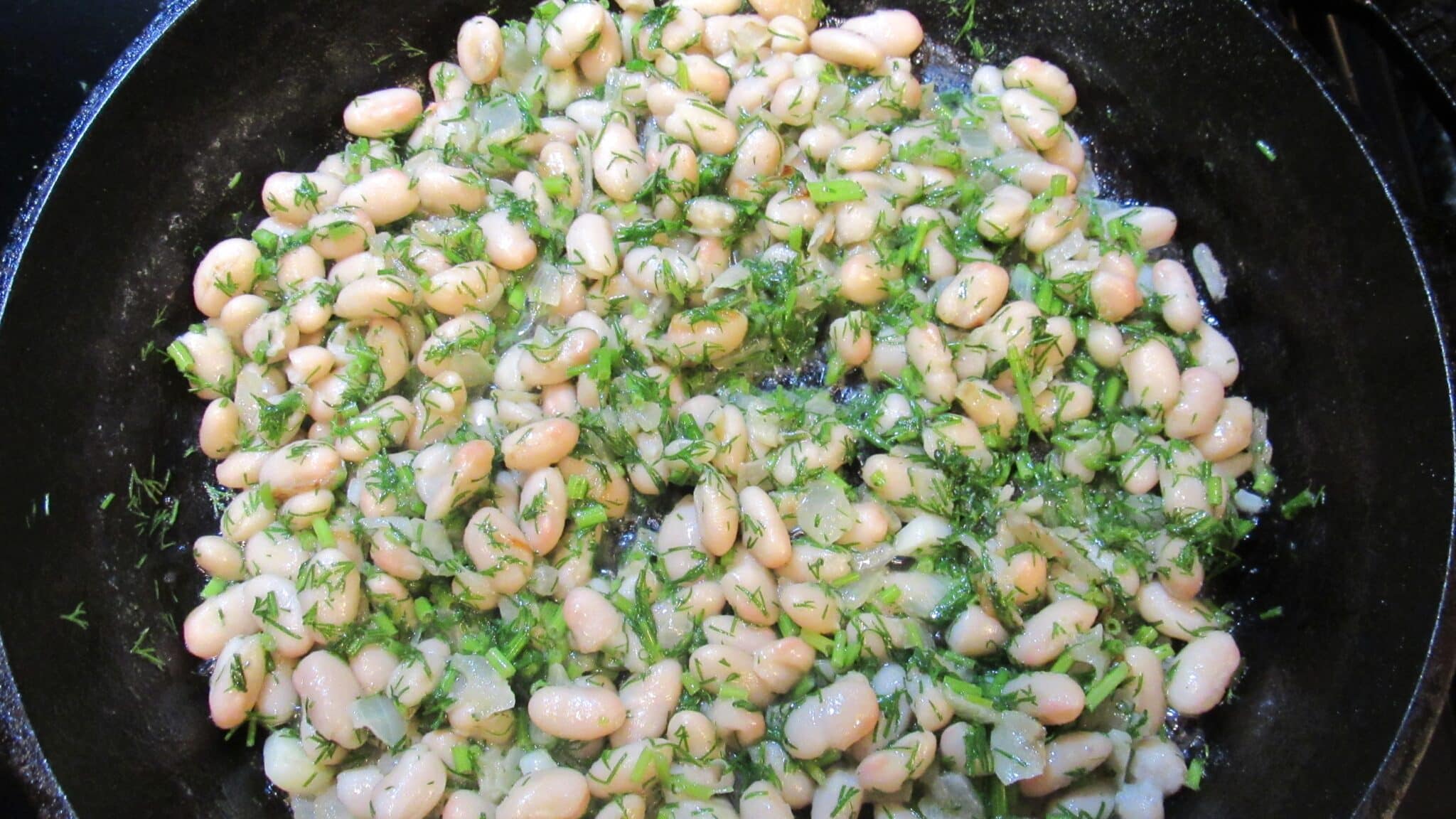 Beans, onion, and dill mixed and cooking.
