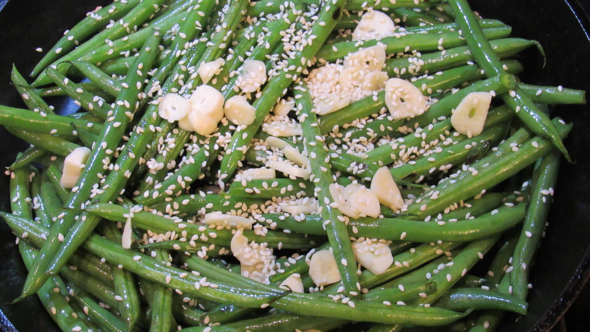 Chopped garlic and sesame seeds are added to the green beans.