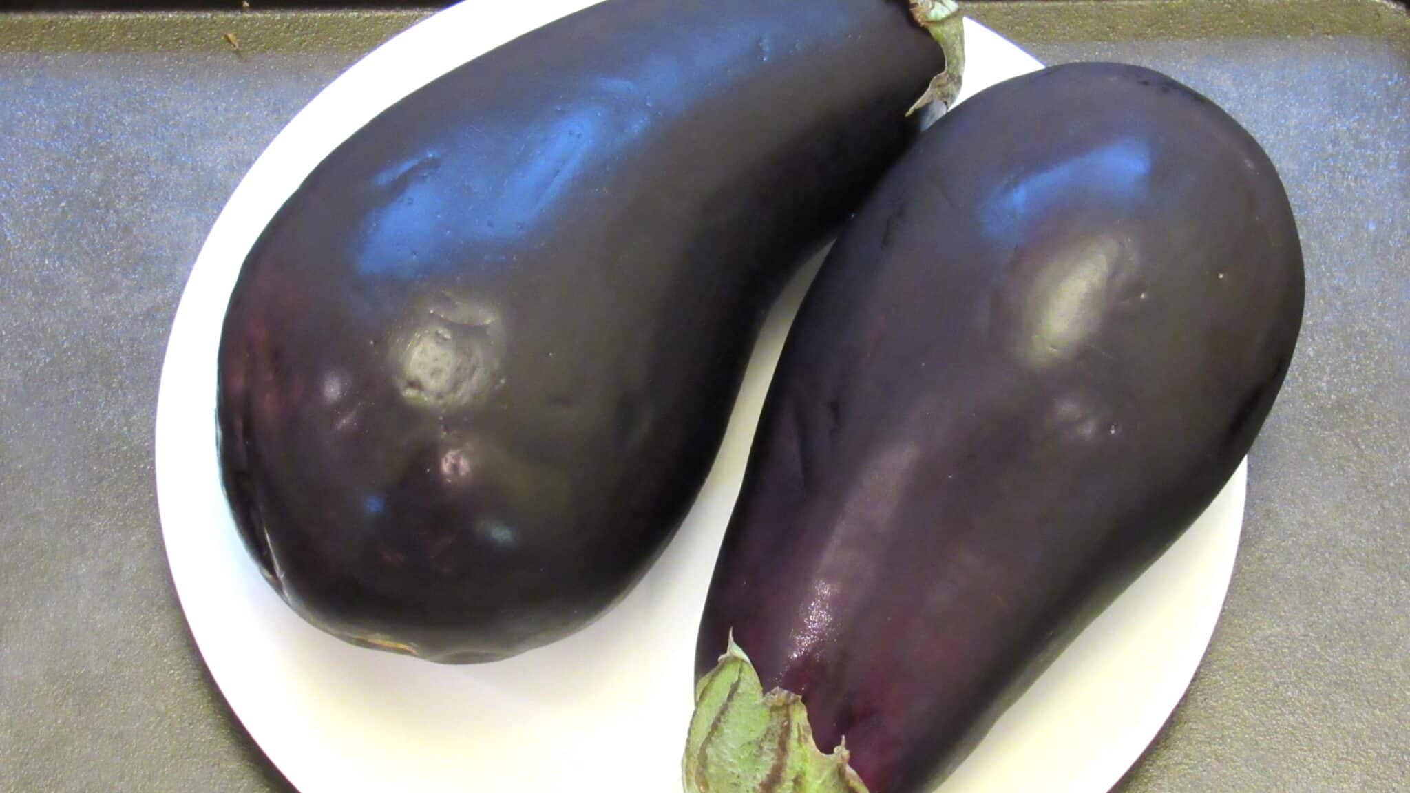 Two globe eggplants on a white plate