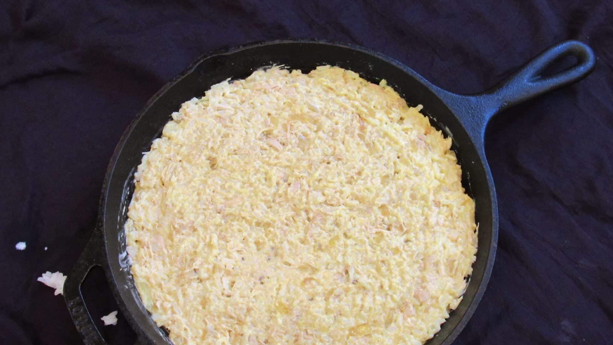  yellow rice and chicken casserole prepared in a cast-iron skillet and ready to bake.