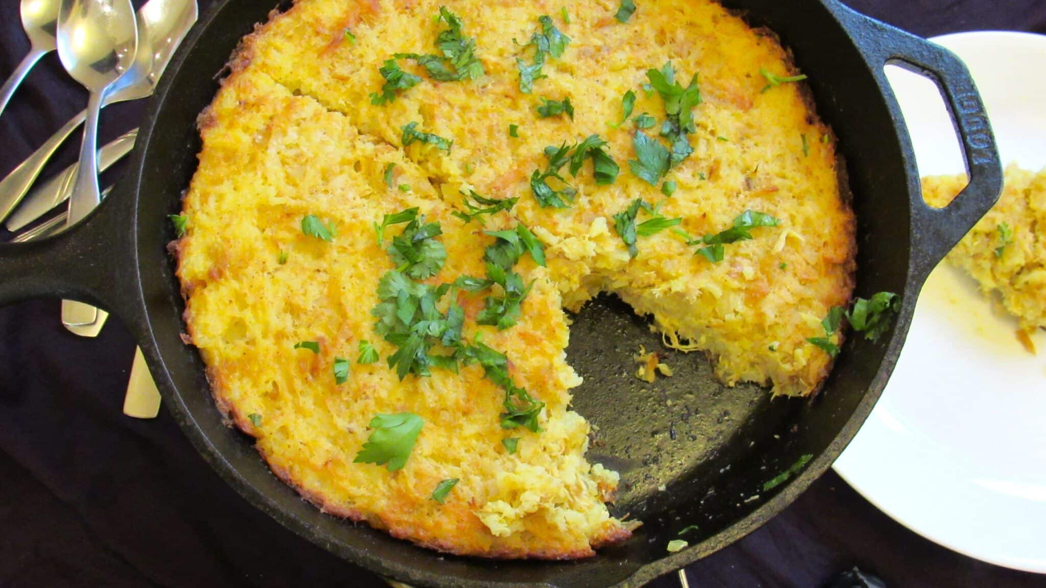 yellow rice and chicken casserole (Tahchin) in cast-iron skillet garnished with parsley and cilantro.