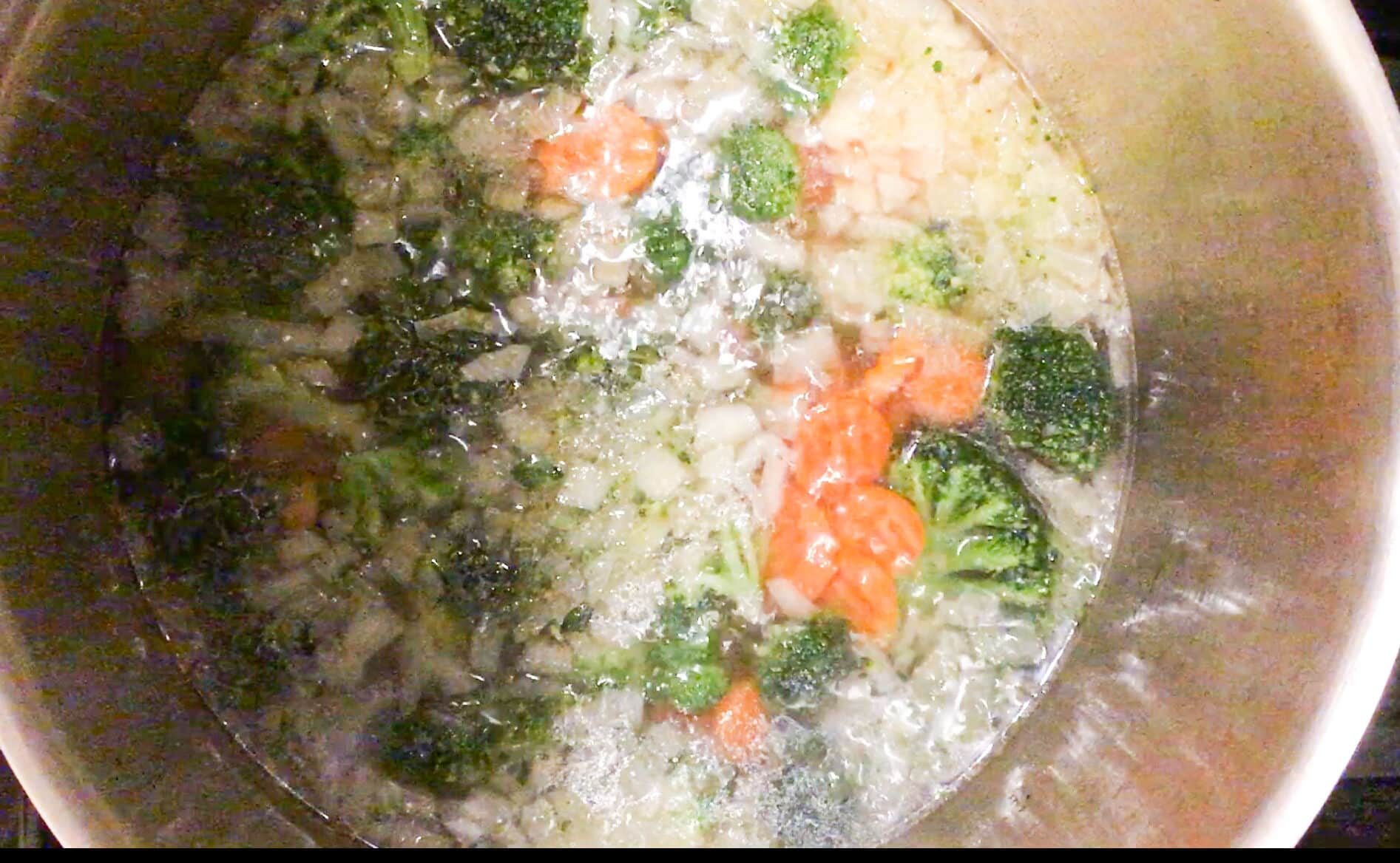 broccoli and carrots and onion in a pot boiling away to make broccoli cheddar soup
