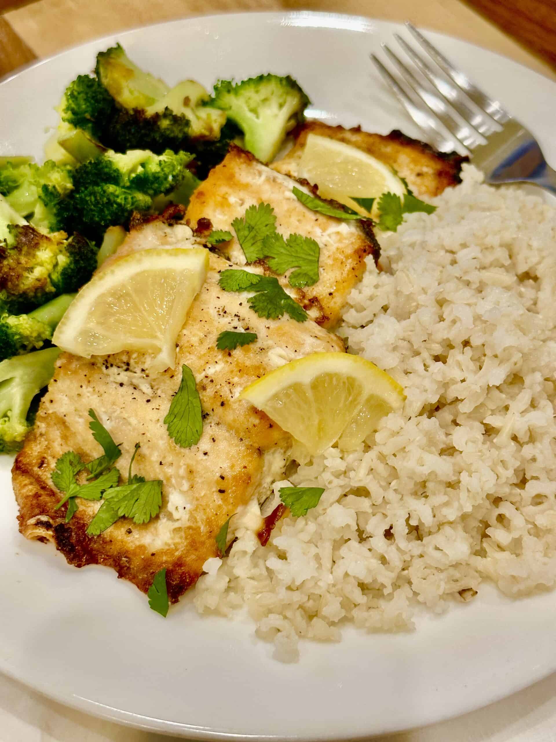 baked frozen salmon served with rice and broccoli on a plate.