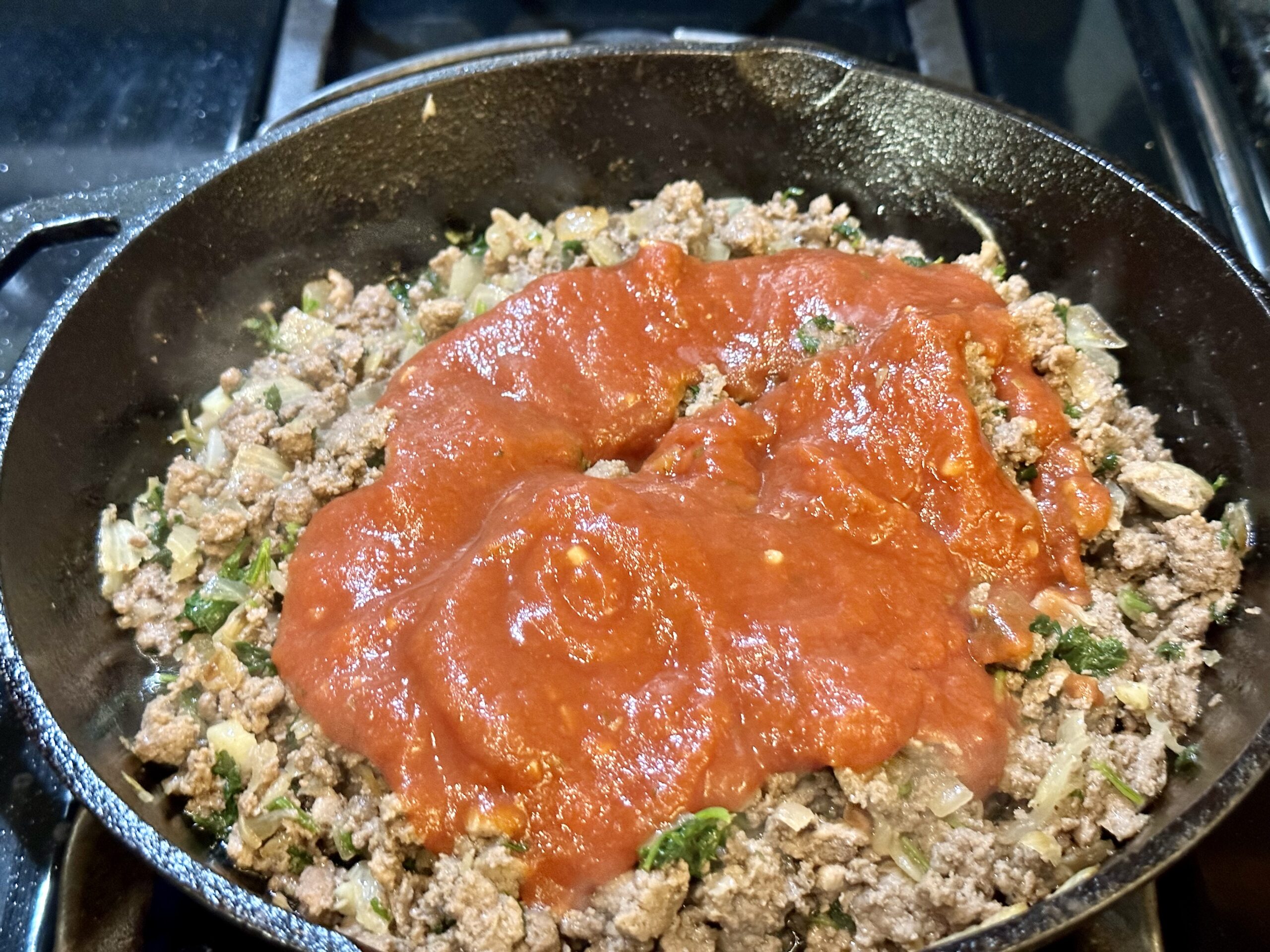 pasta sauce is added to the skillet.