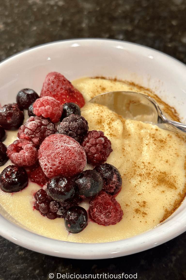 Griessbrei is served on a white bowl with frozen mixed berries.