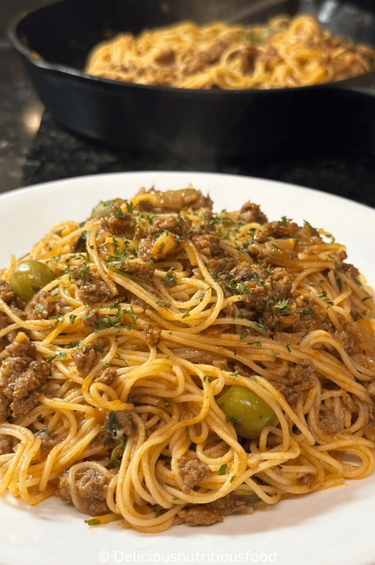 Angel hair pasta with ground beef is served on a white plate.