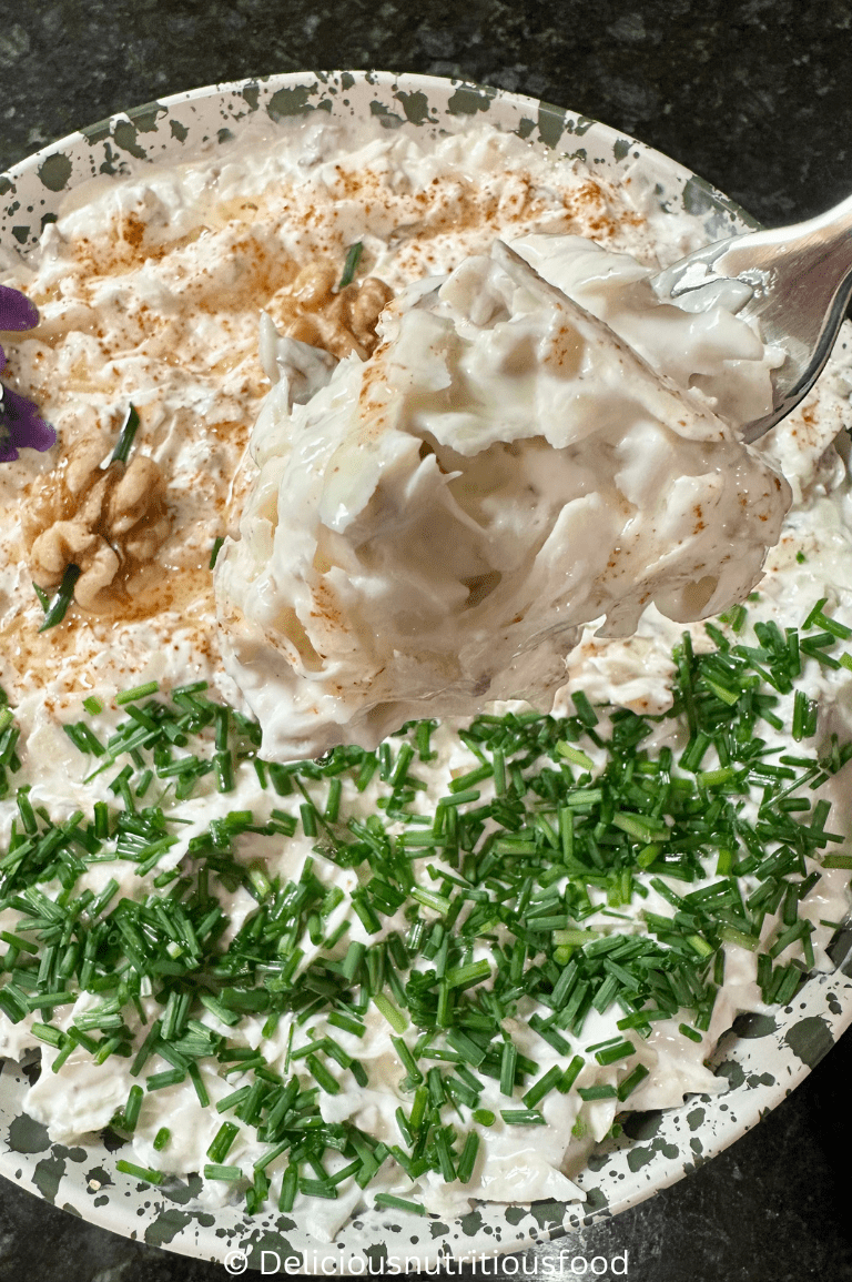 celeriac salad (celery root coleslaw) is served on a plate and garnished with chive, paprika, walnut, and olive oil.
