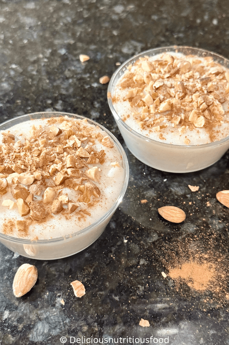 Muhallebi- Middle Eastern milk pudding is served in 2 glass bowls and garnished with chopped almonds and cinnamon.