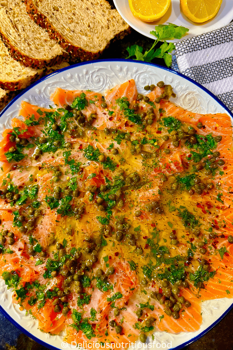Carpaccio de salmon- fresh salmon carpaccio recipe is garnished with caper and fresh chopped herbs and served with bread.